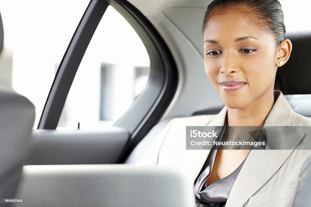 Joven empresaria usando una computadora portátil en el coche - Foto de stock de 20 a 29 años libre de derechos