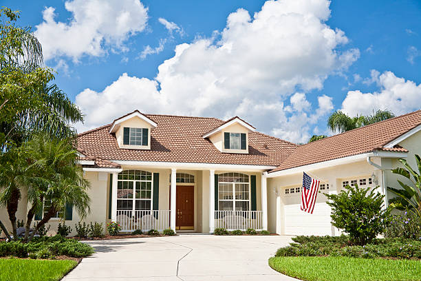 New Home with American Flag "New home with American flag, tile roof, dormer windows, tropical foliage, and green lawn." dormer stock pictures, royalty-free photos & images