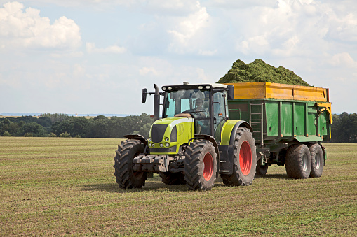 Grass is drived away by tractor from field.