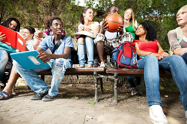 gruppe von teenage freunde sitzen auf der bank. - basketball teenager nature outdoors stock-fotos und bilder