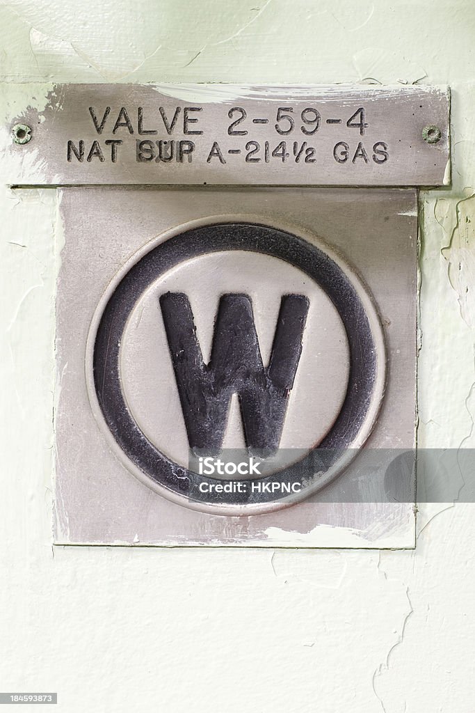 Letter “ W” Old Metal Valve Sign On Painted Green Wall Seen here is a close-up of the letter aWaA as part of a labeling system on an old decommissioned naval ship. Paint Stock Photo