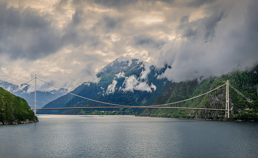 View of Hardanger Bridge over Eidfjord in Norway in summer, fog coverers tops of the mountains