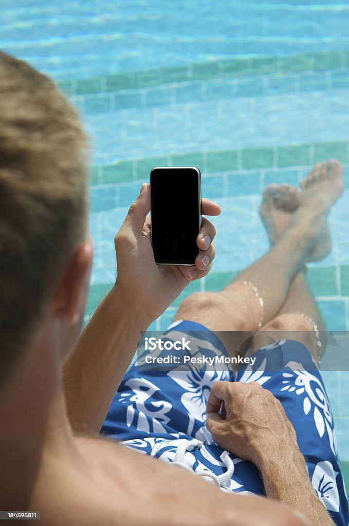 Man Relaxing in Swimming Pool with Smartphone Mobile Phone Over-the-shoulder view of man relaxing in bright swimming pool holding a smartphone (blank for copy space) Mobile Phone Stock Photo