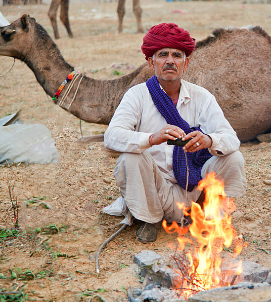 istock Senior Indian man sitting at the fire. Camel in background. 184595977
