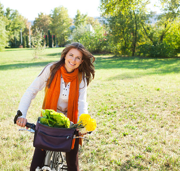 Attractive woman with bicycle in park looking at camera. Autumn colors.