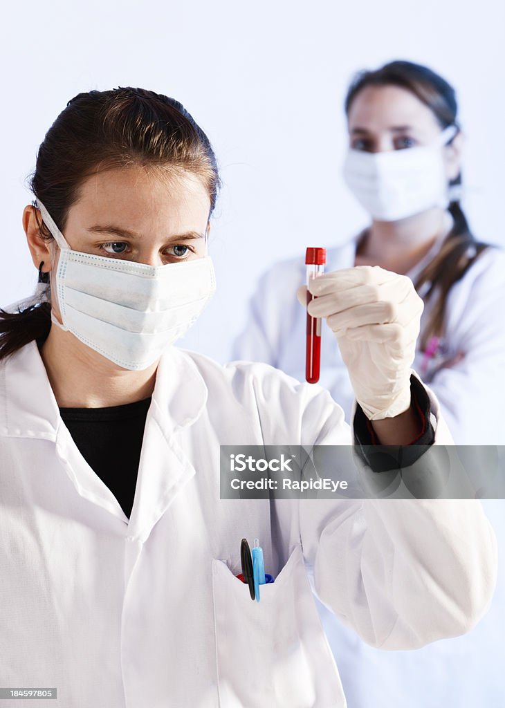 Deux Techniciens de laboratoire étude de jeune femme à la recherche de sérieuses Prélèvement de sang - Photo de Don du sang libre de droits