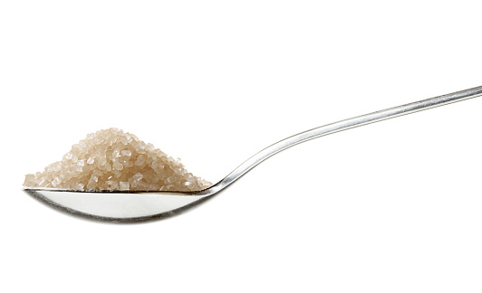 Brown sugar on tea spoon,, sideview isolated on white