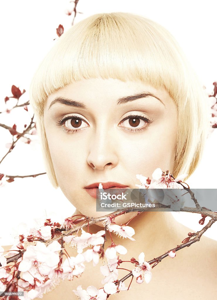 Close-up of a relaxed blonde with pink flowers around her Close-up of an attractive young woman surrounded by pink cherry blossom flowers.  Vertically framed shot. Adult Stock Photo