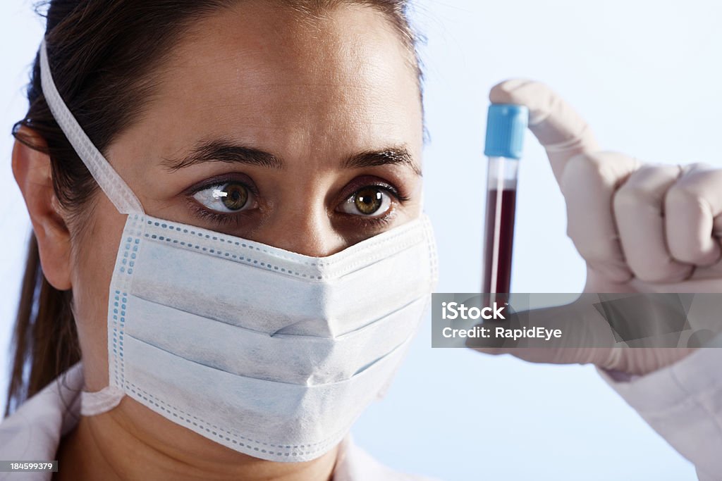 Guanti, maschera Scienziato esamina attentamente fiala di sangue - Foto stock royalty-free di Donazione di sangue