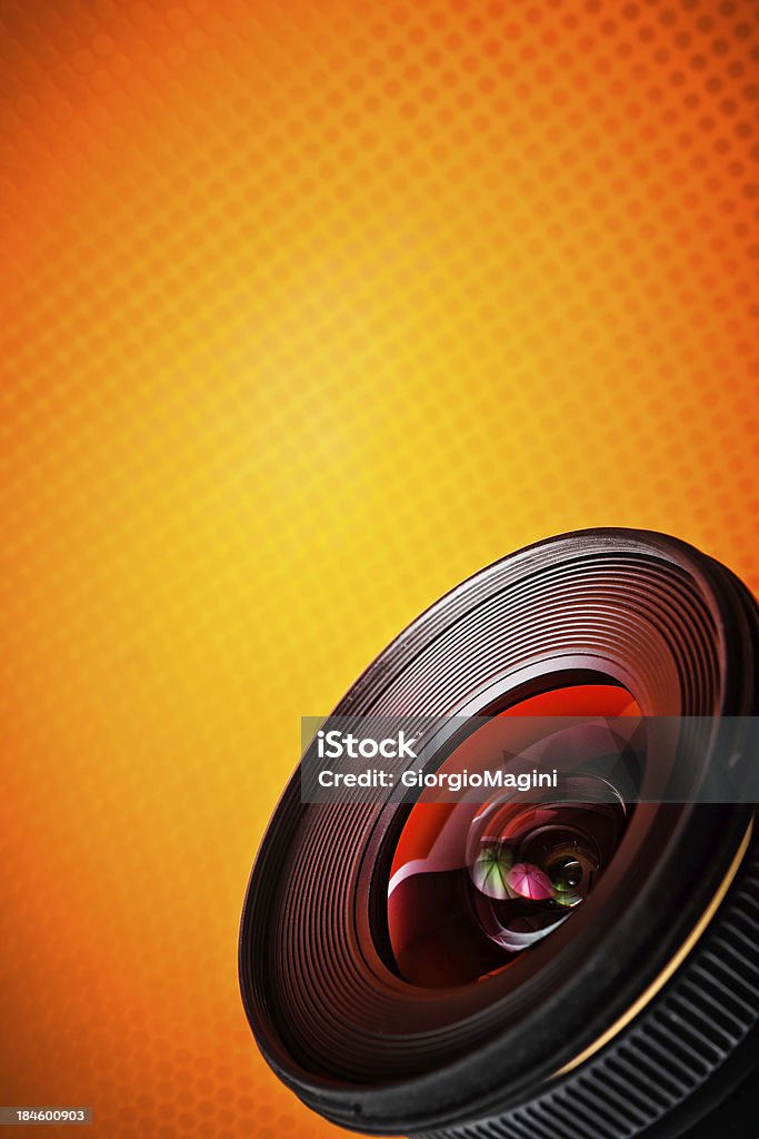 Obiettivo della fotocamera su sfondo arancione - Foto stock royalty-free di Lente - Bulbo oculare