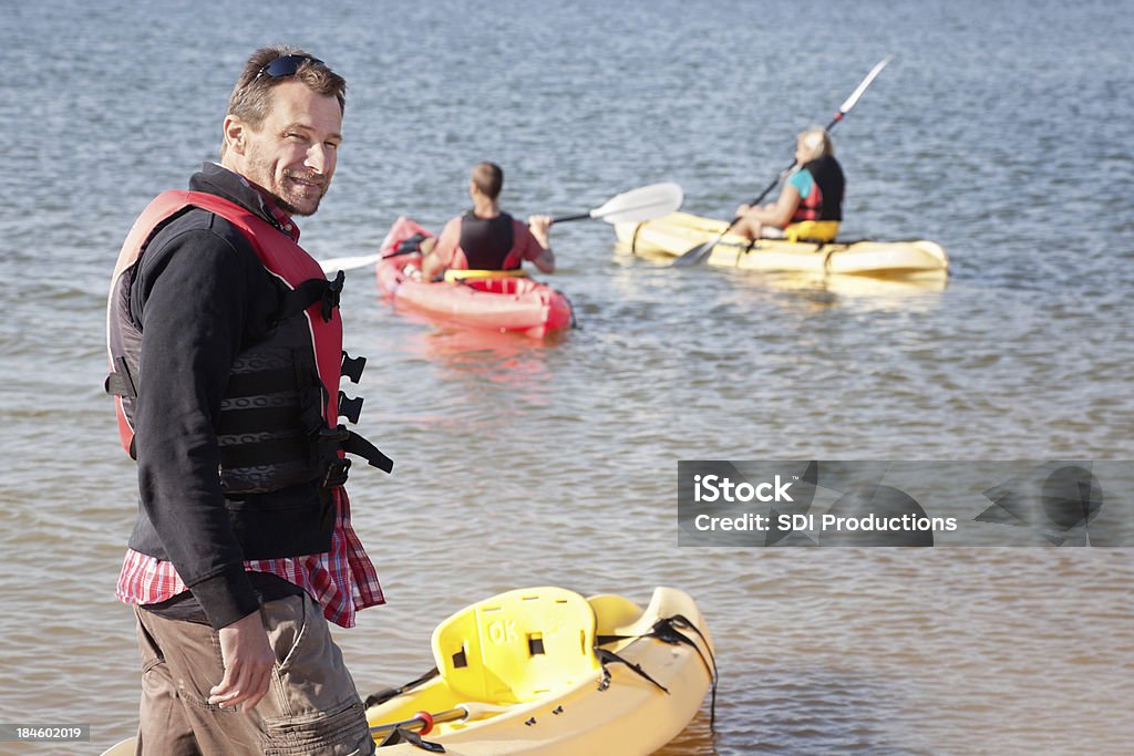 Man looking back before heading out to kayak with friends Man looking back before heading out to kayak with friends. Active Lifestyle Stock Photo