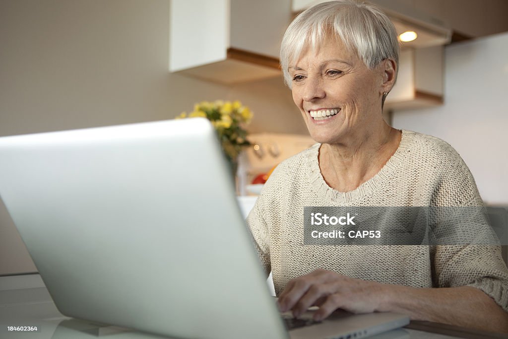 Sênior mulher com o Laptop na cozinha - Foto de stock de 70 anos royalty-free