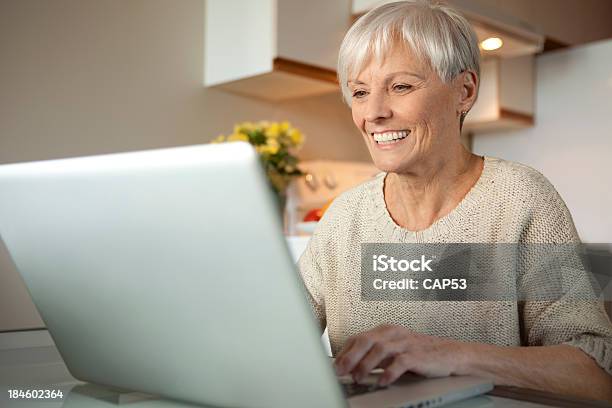 Foto de Sênior Mulher Com O Laptop Na Cozinha e mais fotos de stock de 70 anos - 70 anos, Adulto, Adulto maduro