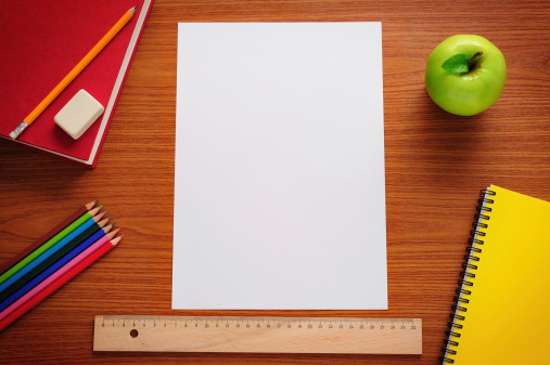 Blank paper and school supplies on desk.