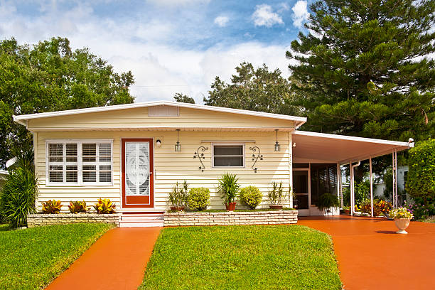 A mobile home with car port and grassy garden Mobile home located in a trailer park. Front yard, driveway and sidewalk. Manufactured home; static caravan. manufactured housing stock pictures, royalty-free photos & images