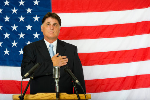 A politician swearing in against the American flagClick Here for More of this Series