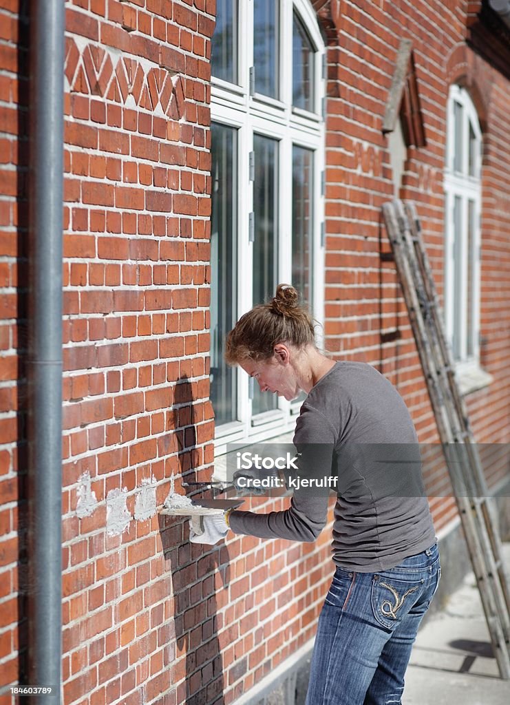 Weibliche Maurer reparieren house - Lizenzfrei Alt Stock-Foto