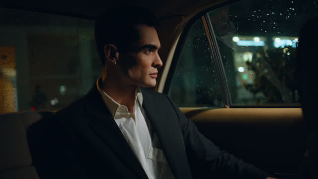 Handsome businessman looking car window at night closeup. Man travelling auto