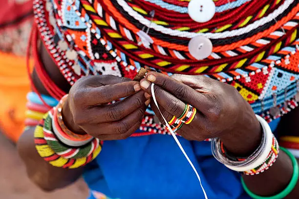 "Close-up of the hands of a Samburu woman doing beadwork. Kenya, Africa."