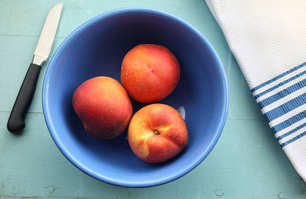 Bowl of Peaches on Blue Table stock photo