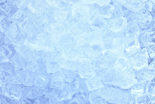 Ice cubes with drops of melt water water on a blue background, top view.
