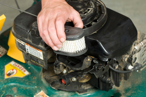 A male hand is replacing a lawnmoweraas air cleaner.