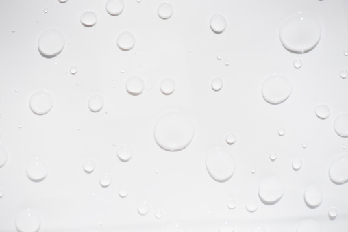 water drops on white. White water bubbles on the surface ripples. Defocus blurred transparent white-black colored clear calm water surface texture with splash and bubbles. Water waves shining.