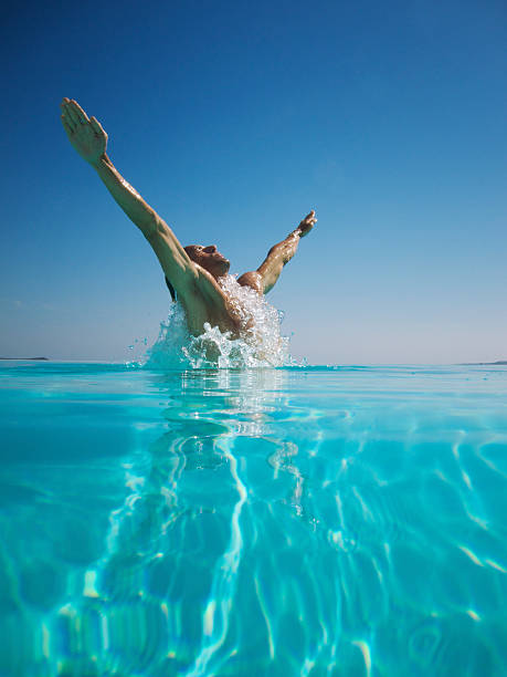 istock Athletic Young Man Emerging From Turquoise Swimming Pool Arms Spread 184606699