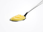 A spoon with custard on a white background