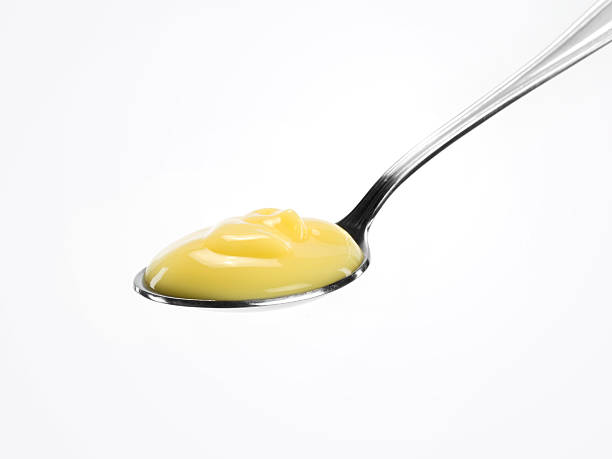 A spoon with custard on a white background Close up of a spoonful of custard on white background custard stock pictures, royalty-free photos & images