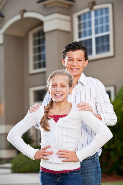 istock Brother and sister standing outside house 184607138