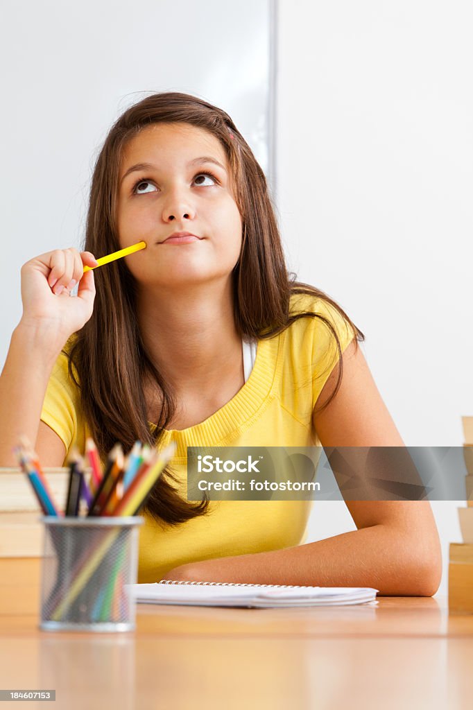 Student Thinking Elementary age schoolgirl sitting by the desk in the classroom, thinking. Adult Stock Photo