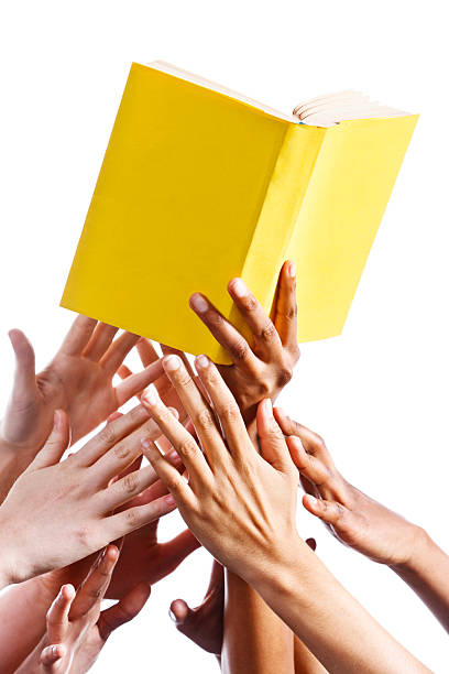 istock Many hands grabbing for yellow book. Isolated on white. 184607486