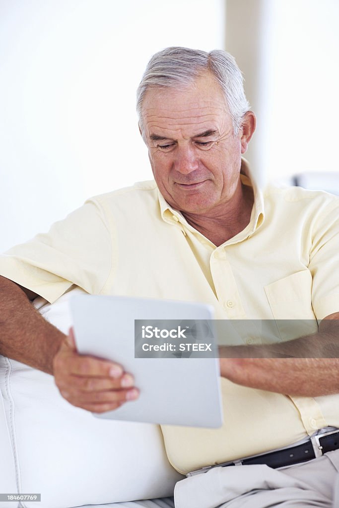 Uomo anziano utilizzando tablet PC sul divano - Foto stock royalty-free di 60-69 anni