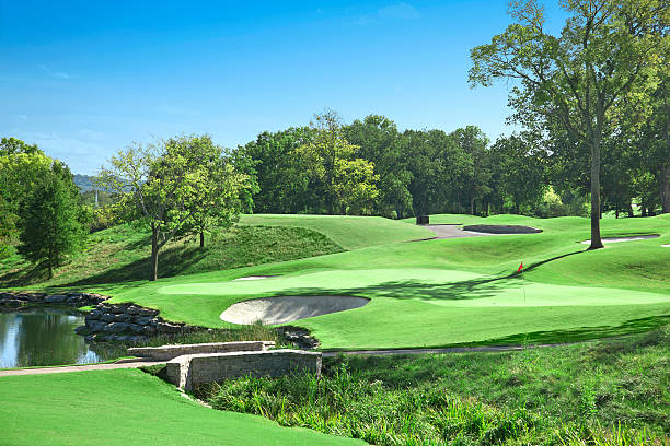 Golf Course "A close up of a green with flag marking the hole at a golf course, surrounded by sand penalty bunkers and a water hazard." country club stock pictures, royalty-free photos & images