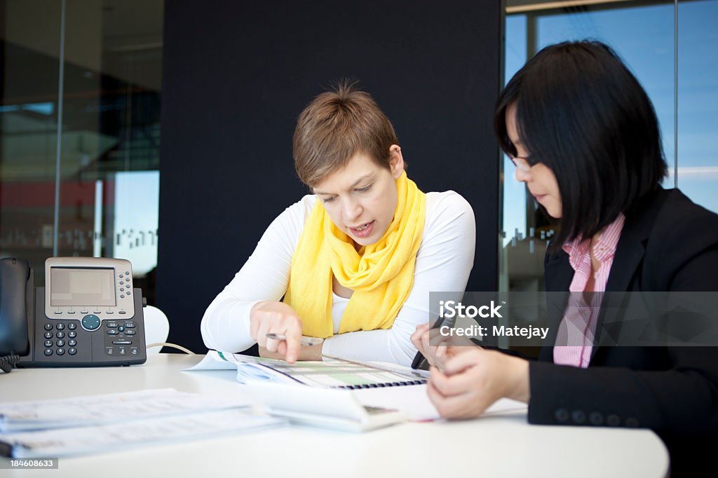 Two young female professionals working Young accountants or financial analysts focussing on their work in a modern, brightly lit office Adult Stock Photo