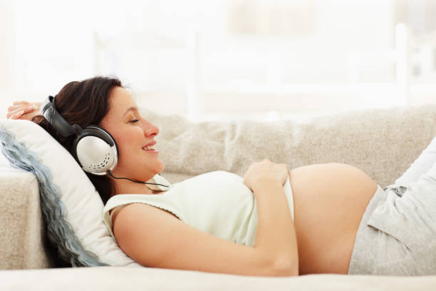 détendue femme enceinte heureuse, profitant de la musique - lying on side audio photos et images de collection