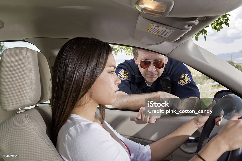 Young Woman Stopped by Officer with Tears Tears roll down the cheek of this young woman as she is pulled over by a police officer. Focus on officer's face. Police Force Stock Photo