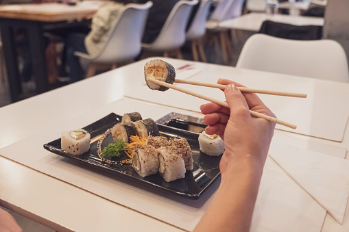 Sushi roll with Chinese chopsticks in restaurant photo