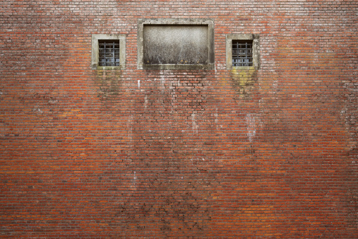 High wall with a few barred windows.