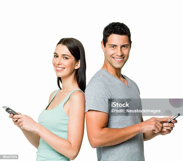 Foto de Jovem Casal Com Telefones Celulares No Fundo Branco e mais fotos de stock de Fundo Branco