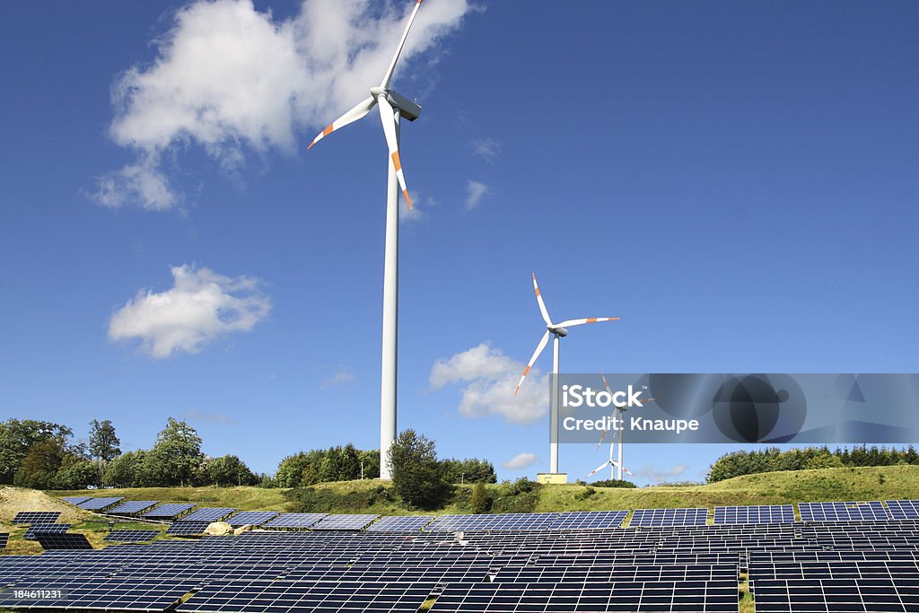 Eoliennes derrière le champ de panneaux solaires sous ciel clair - Photo de Arbre libre de droits