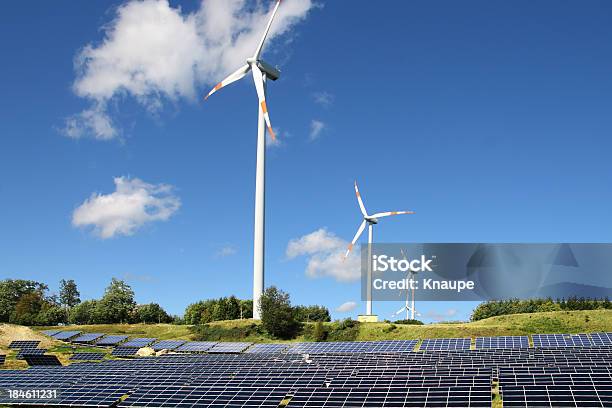 Photo libre de droit de Eoliennes Derrière Le Champ De Panneaux Solaires Sous Ciel Clair banque d'images et plus d'images libres de droit de Arbre