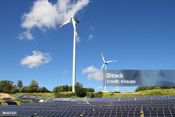 Turbinas Eólicas Atrás De Campo Dos Painéis Solares Com Céu Claro - Fotografias de stock e mais imagens de Ao Ar Livre