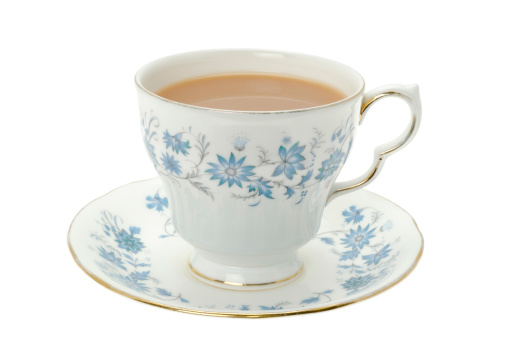 A cup of hot tea served in an ornate blue patterned bone china cup and saucer - studio shot.