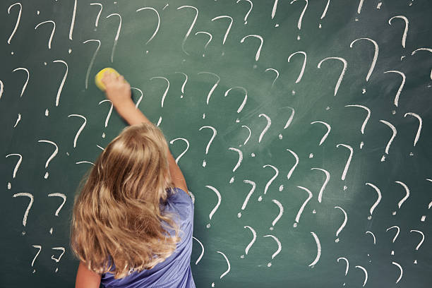 istock Little school girl erasing question marks on blackboard 184611907