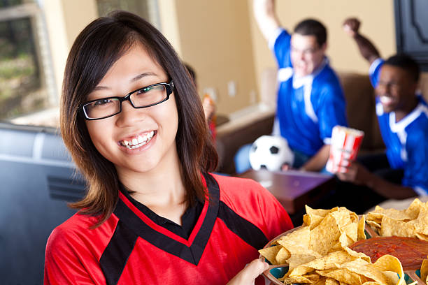 istock Smiling spouse or girlfriend holding snacks for guys  watching game 184613626