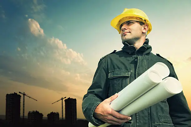 Photo of Construction worker on a construction site with blue prints.