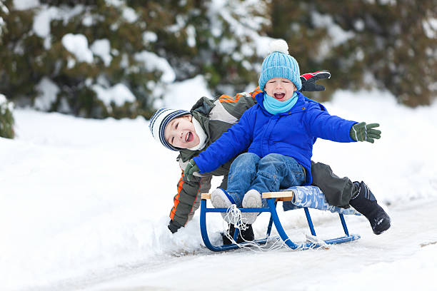 istock Two Little Boys Sledding On Snow 184616469
