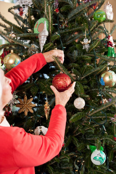 istock Senior woman wearing red, decorating Christmas tree 184617175